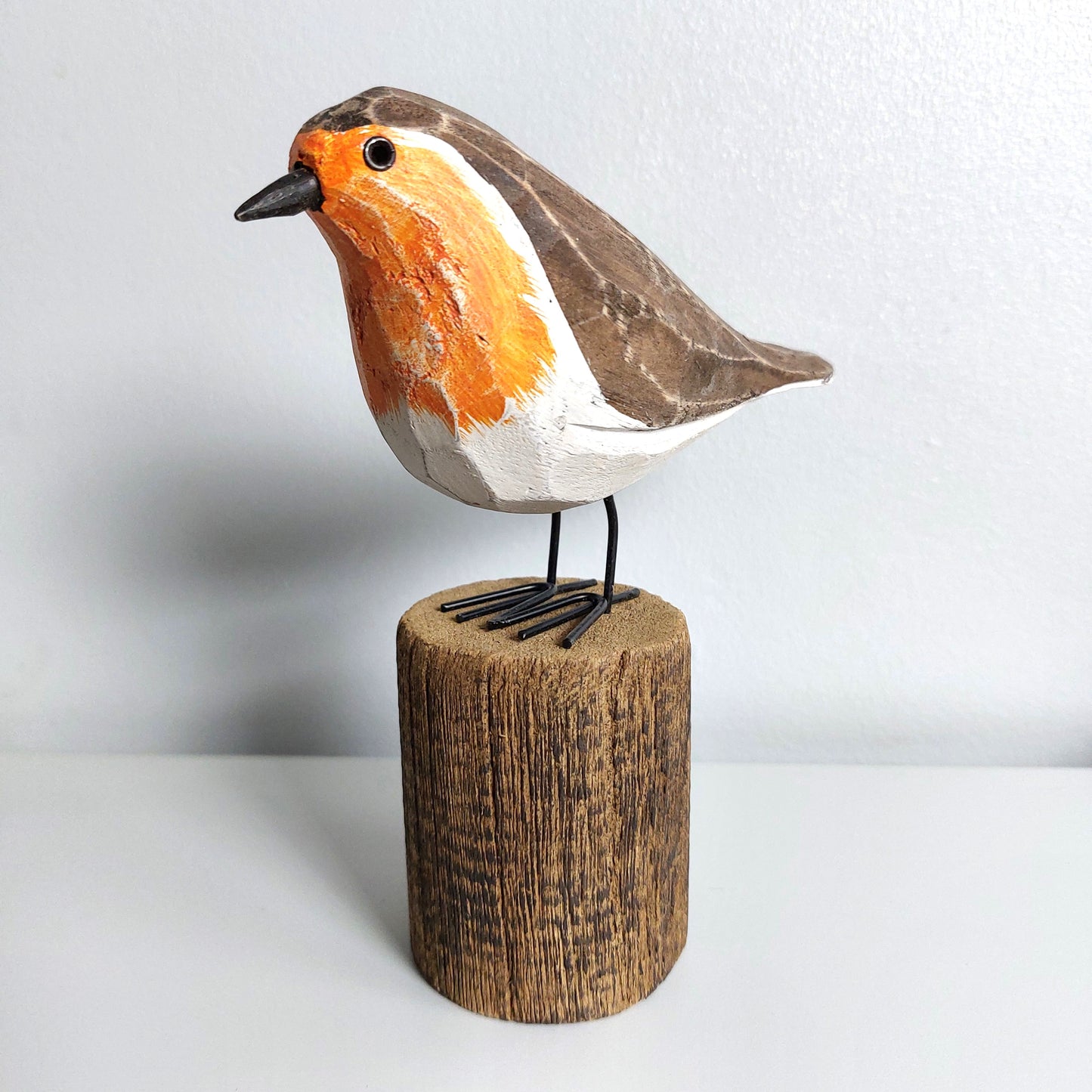 Wooden bird figurine on a wooden base against a white background