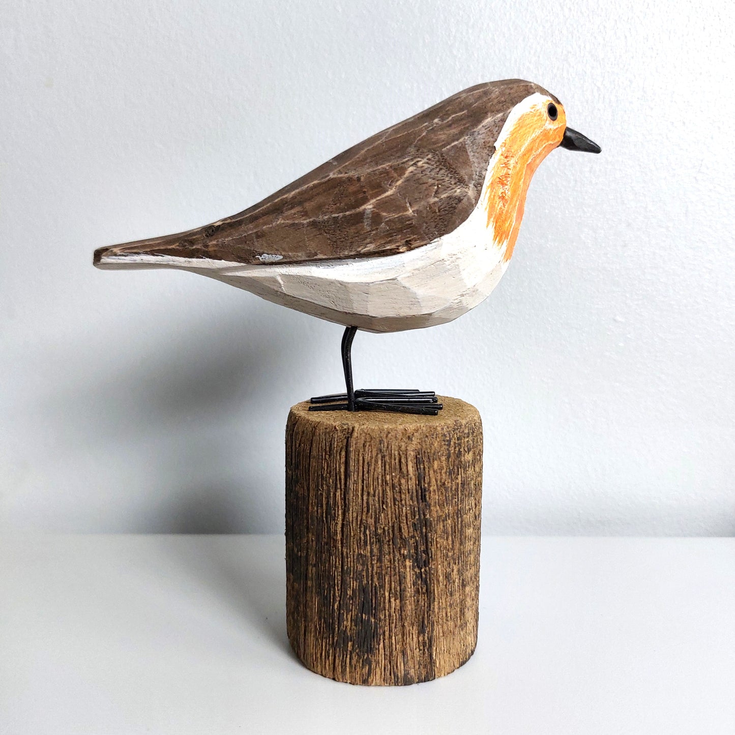 Wooden bird figurine on a cylindrical wooden base against a light background