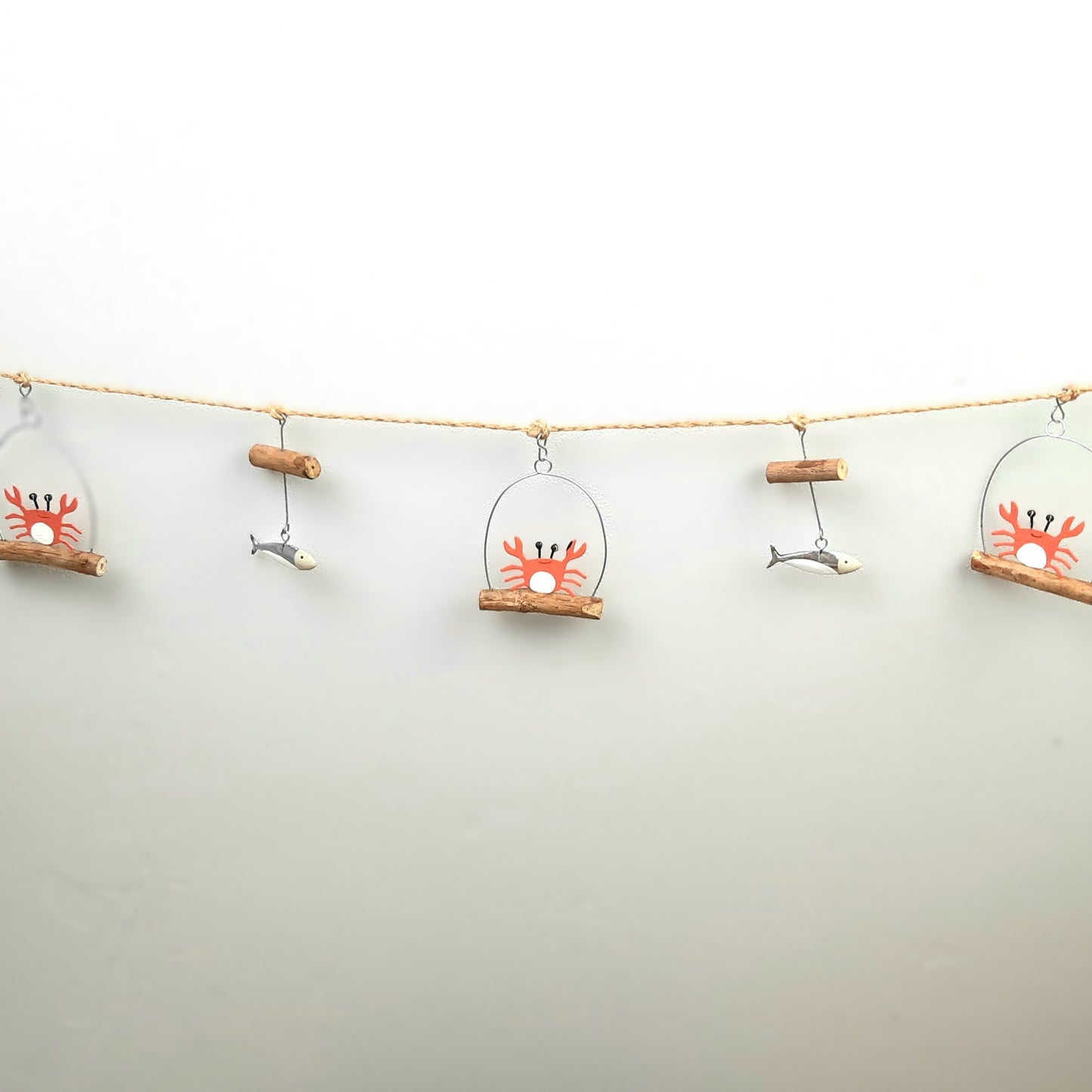 Decorative string with crab and fish ornaments on a plain background