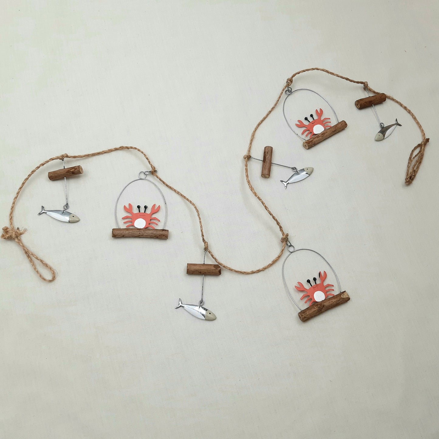 Decorative wall hanging with crab and fish designs on a beige background