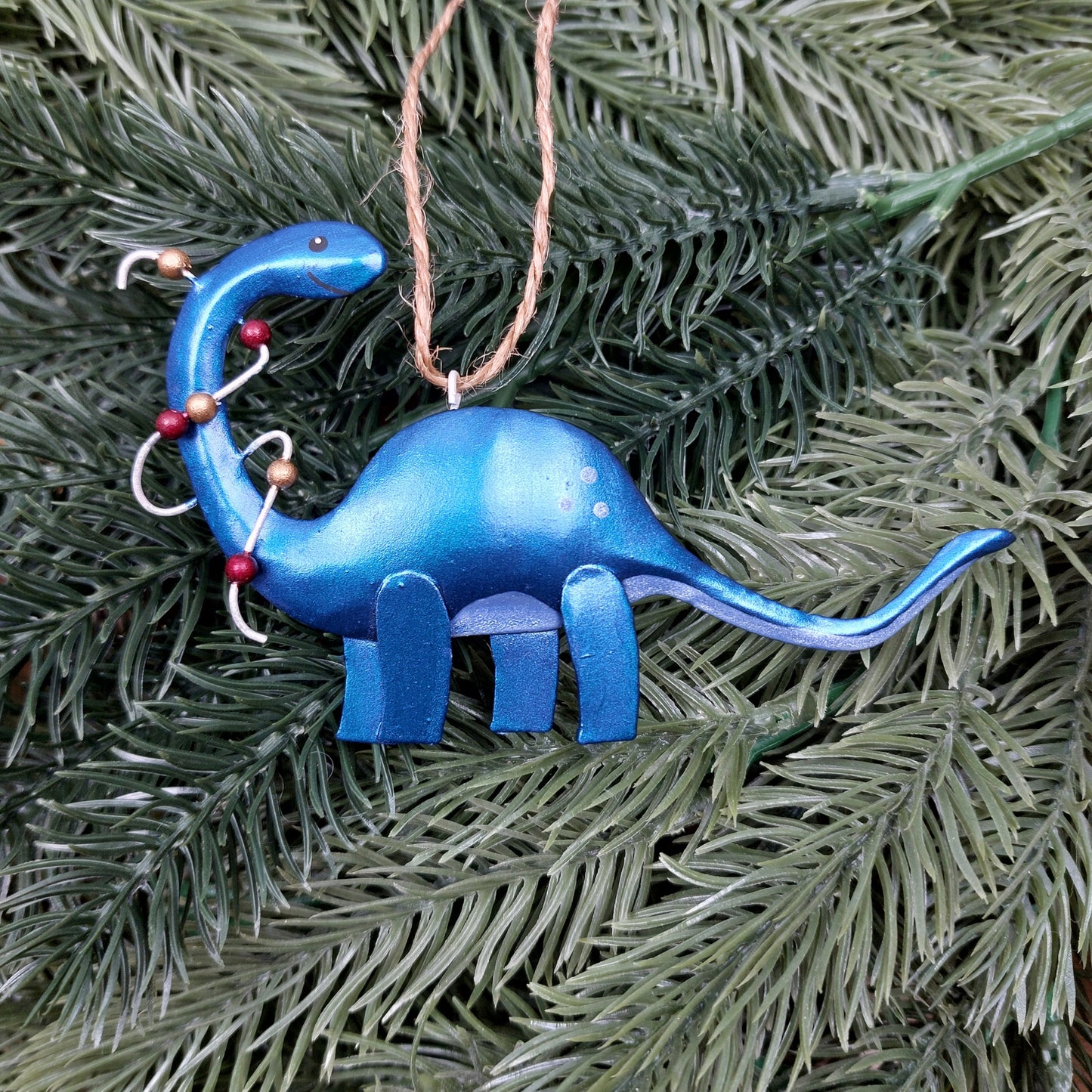Blue dinosaur with Christmas lights ornament hanging on a Christmas tree