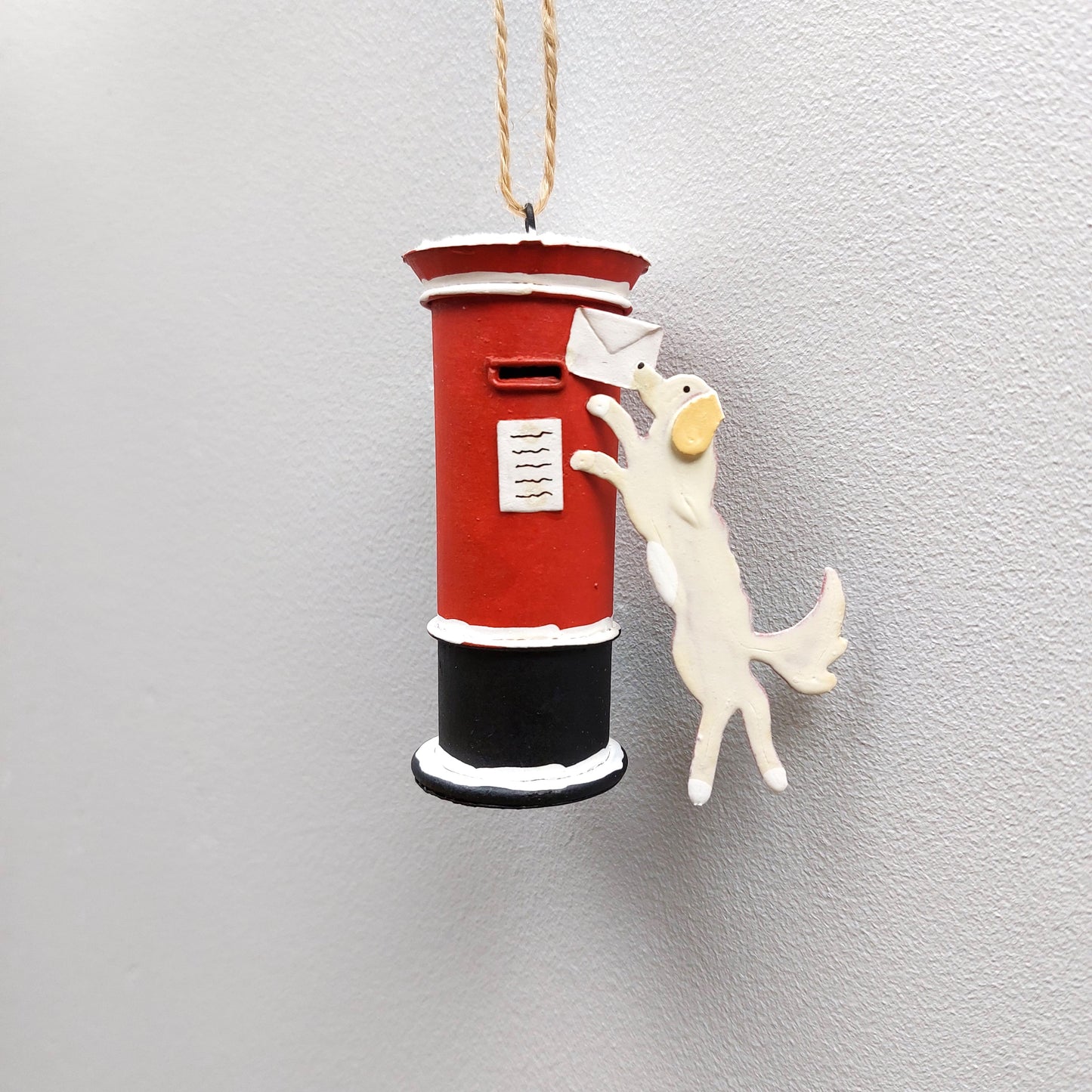 Hanging letterbox with a dog holding a letter ornament against a pale background