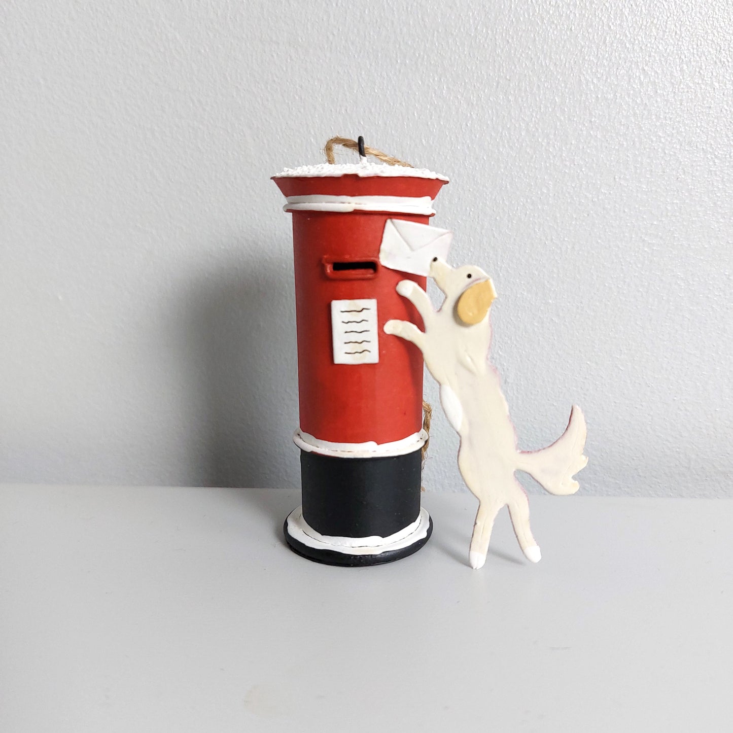 Red mailbox with a dog with a letter ornament next to it on a light gray background