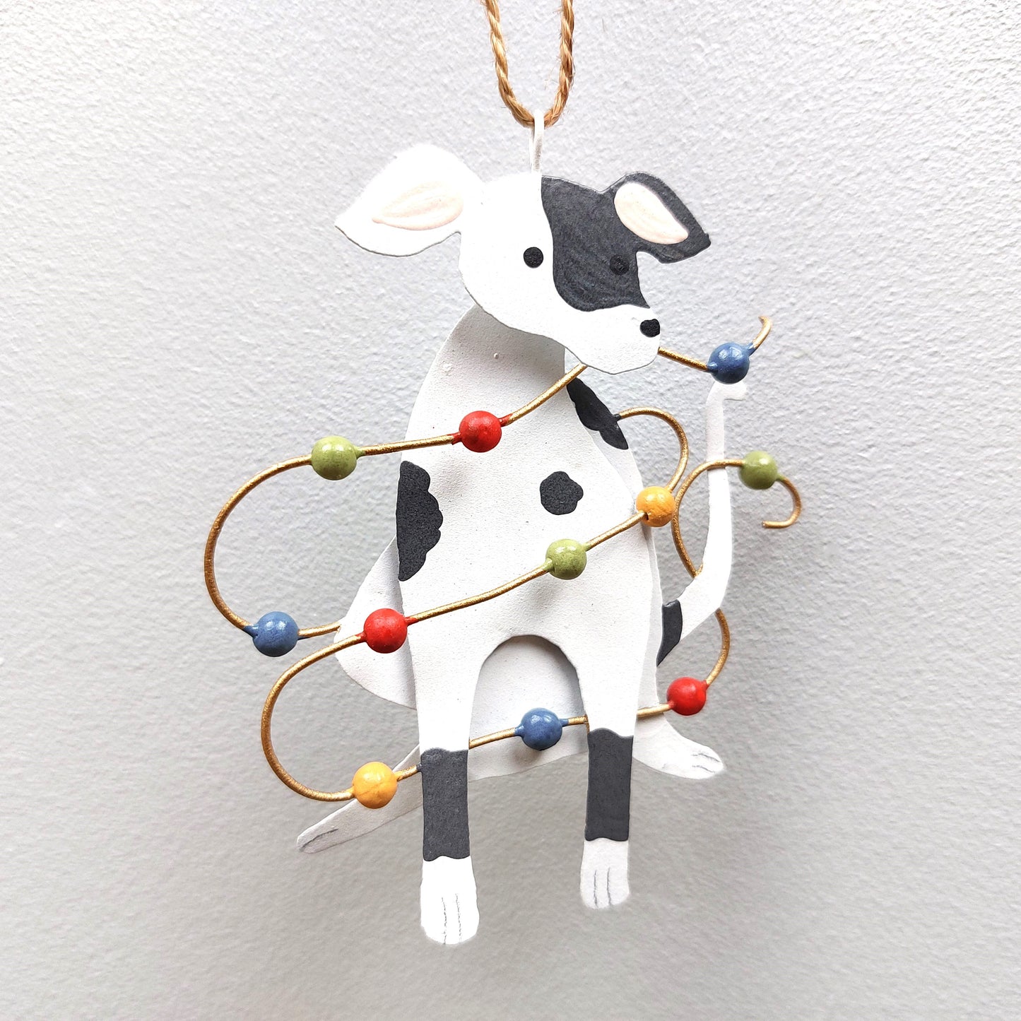 A tin spotty dog decoration with Christmas lights against a white background