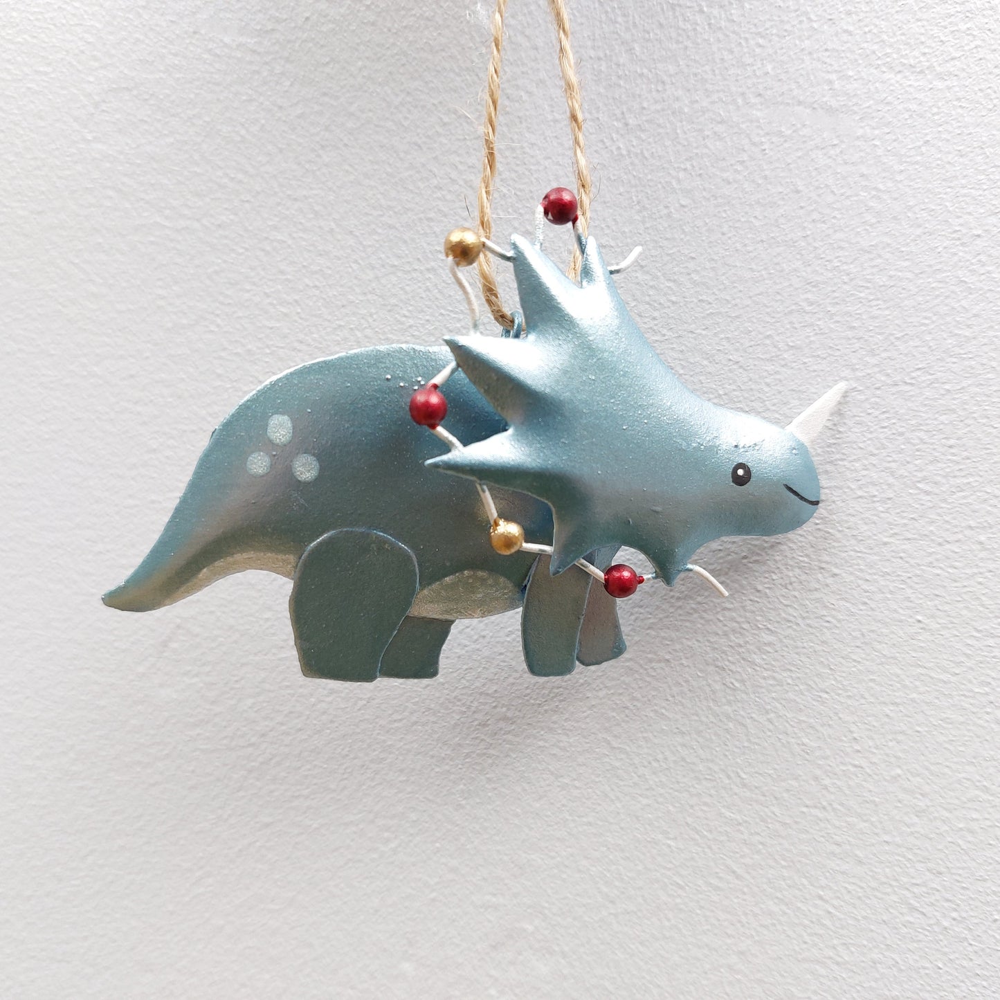 Decorative green dinosaur ornament with Christmas lights on a white background