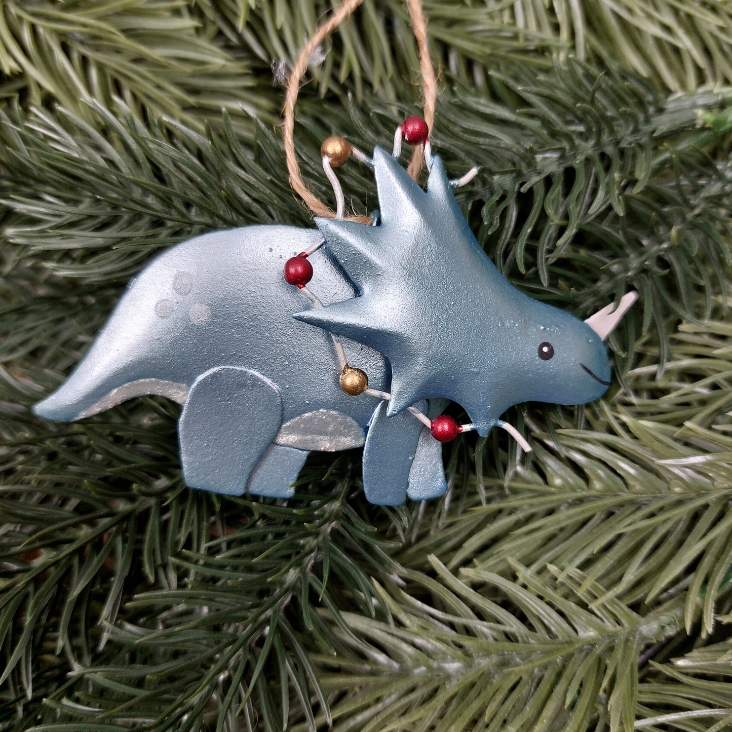 Decorative dinosaur hanging ornament on a faux green pine branch
