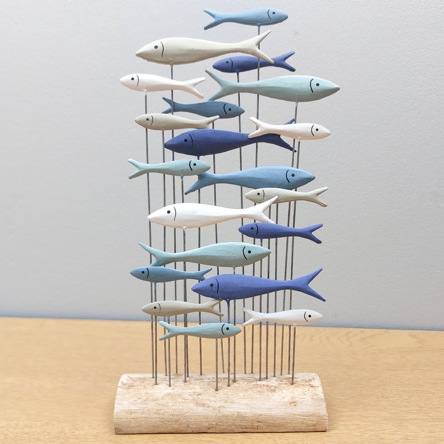 Decorative metal sculpture of colourful fish on a stand with a plain background