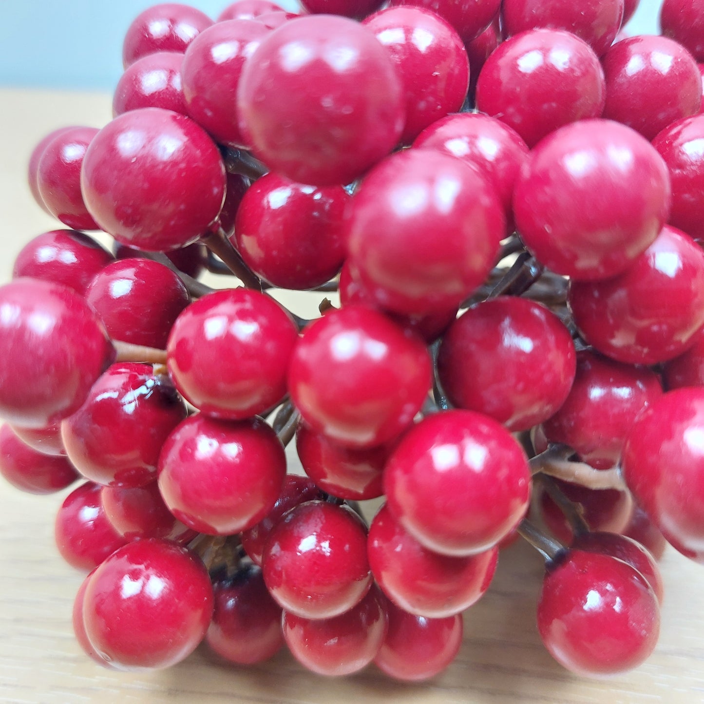 Close-up of artificial red Cranberries on a light wooden surface
