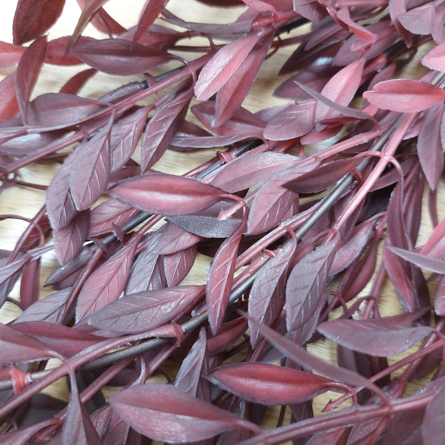 Close-up of red artificial huckleberry leaves on a wooden surface