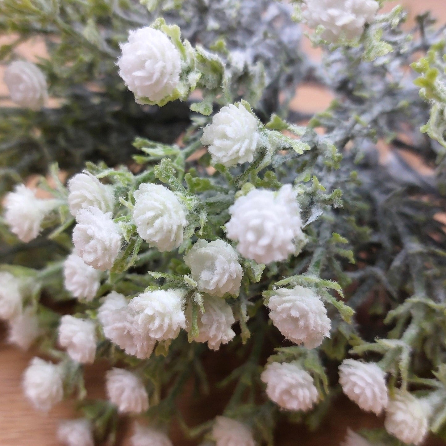 Close-up of an artificial White Gyp bunch of flowers and green leaves.