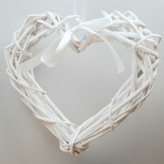 A hanging White Colour Wicker Heart with a white satin ribbon and bow.