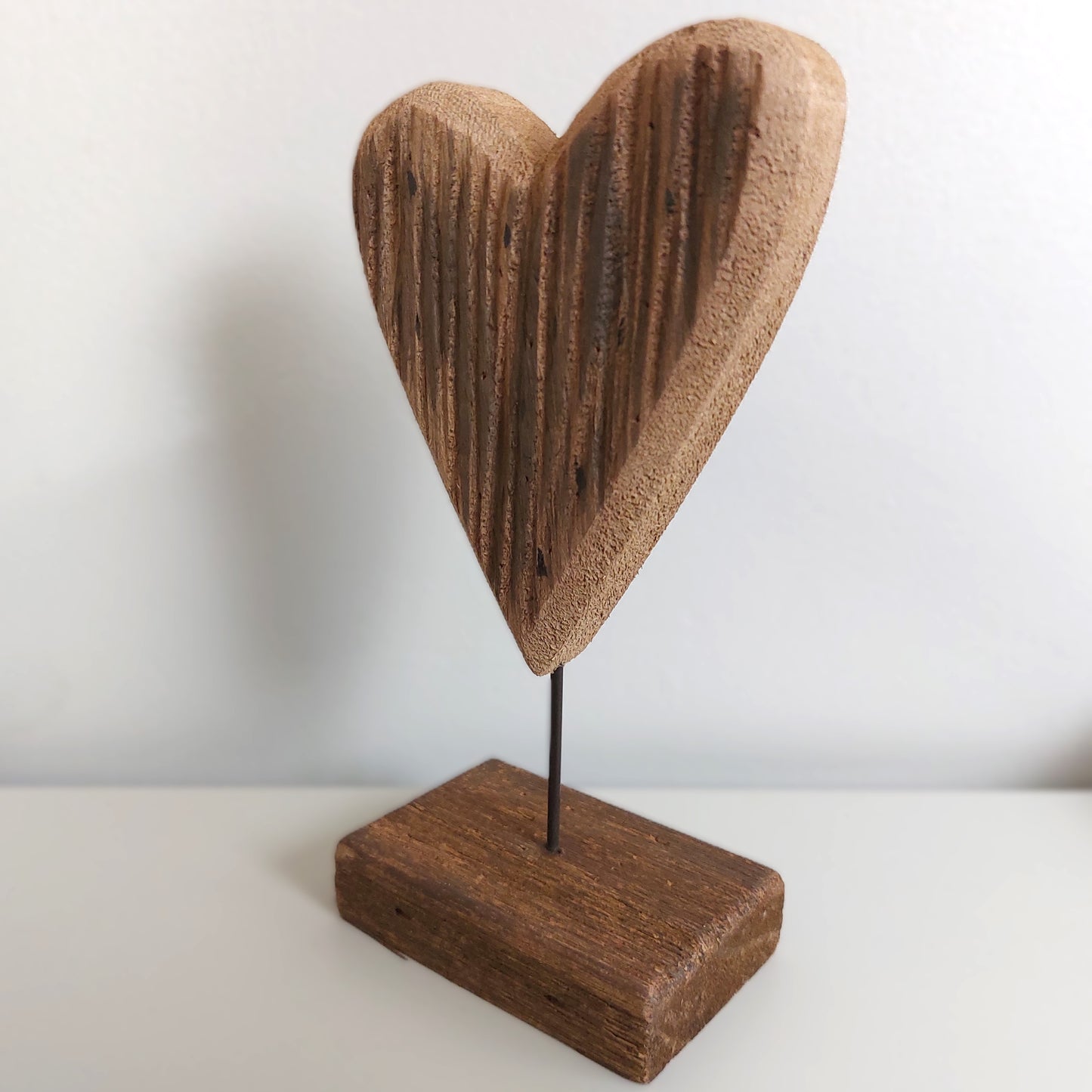 Wooden heart-shaped object on a stand against a white background