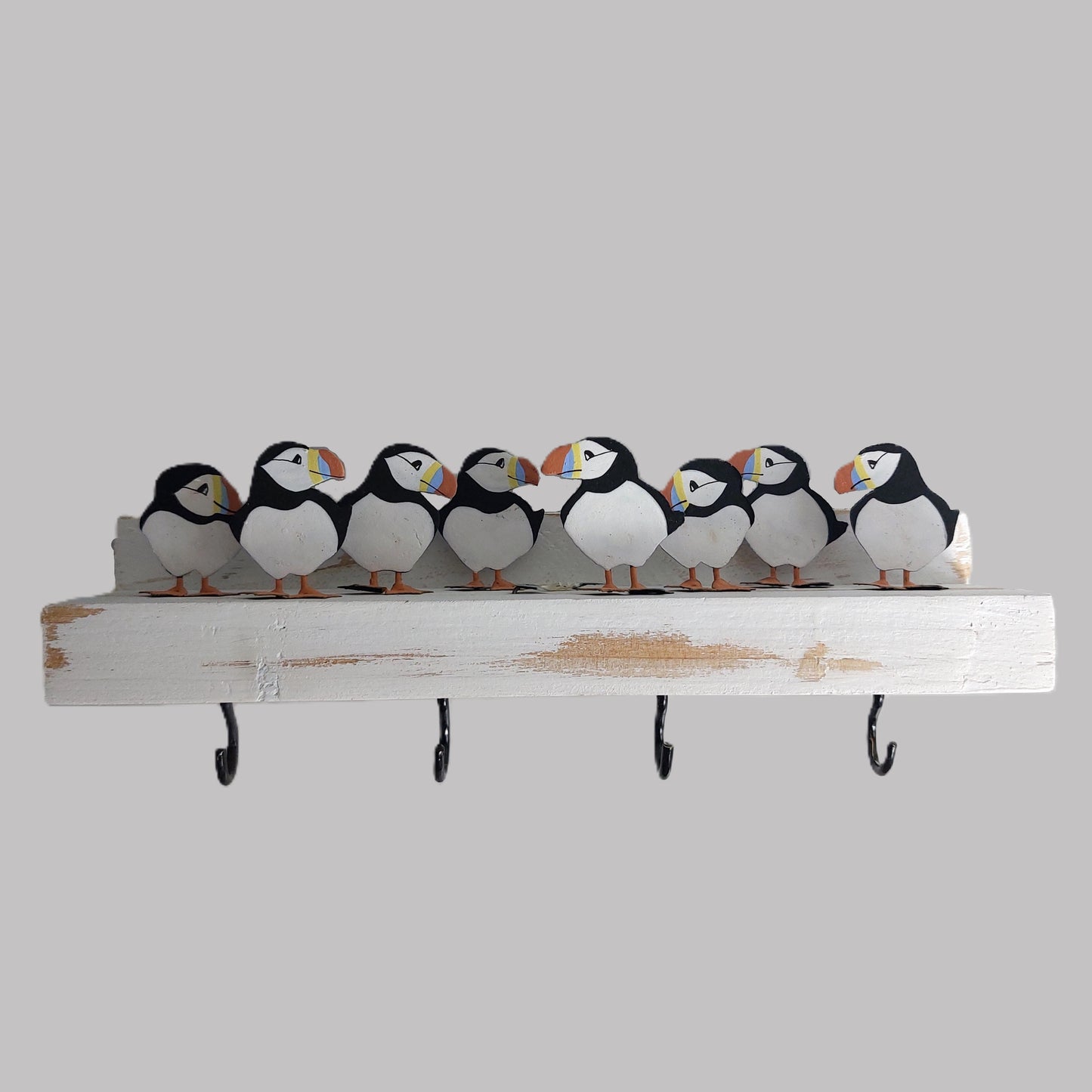 Decorative key rack with puffin figurines and hooks on a gray background