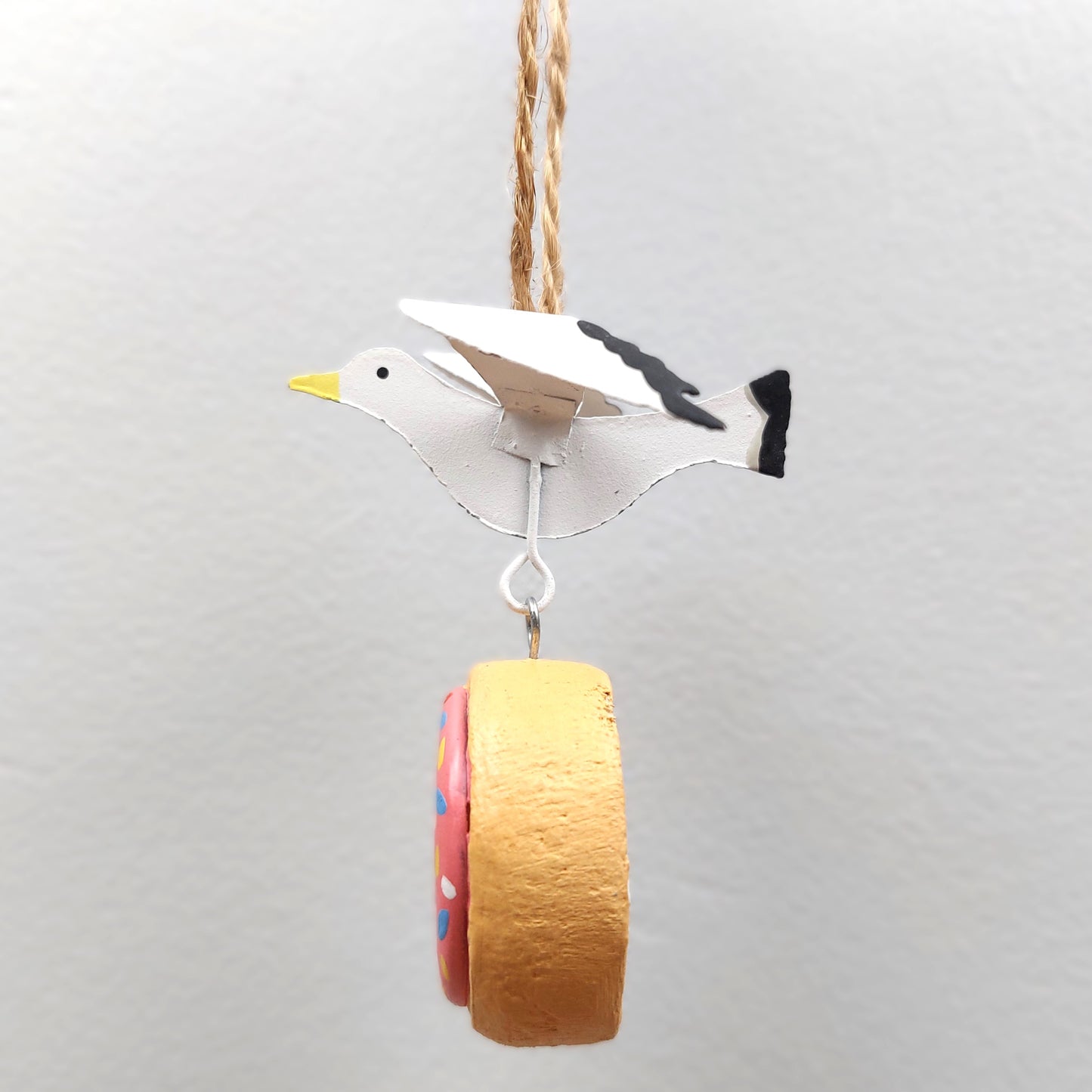 Decorative bird ornament with a colorful doughnut on a gray background