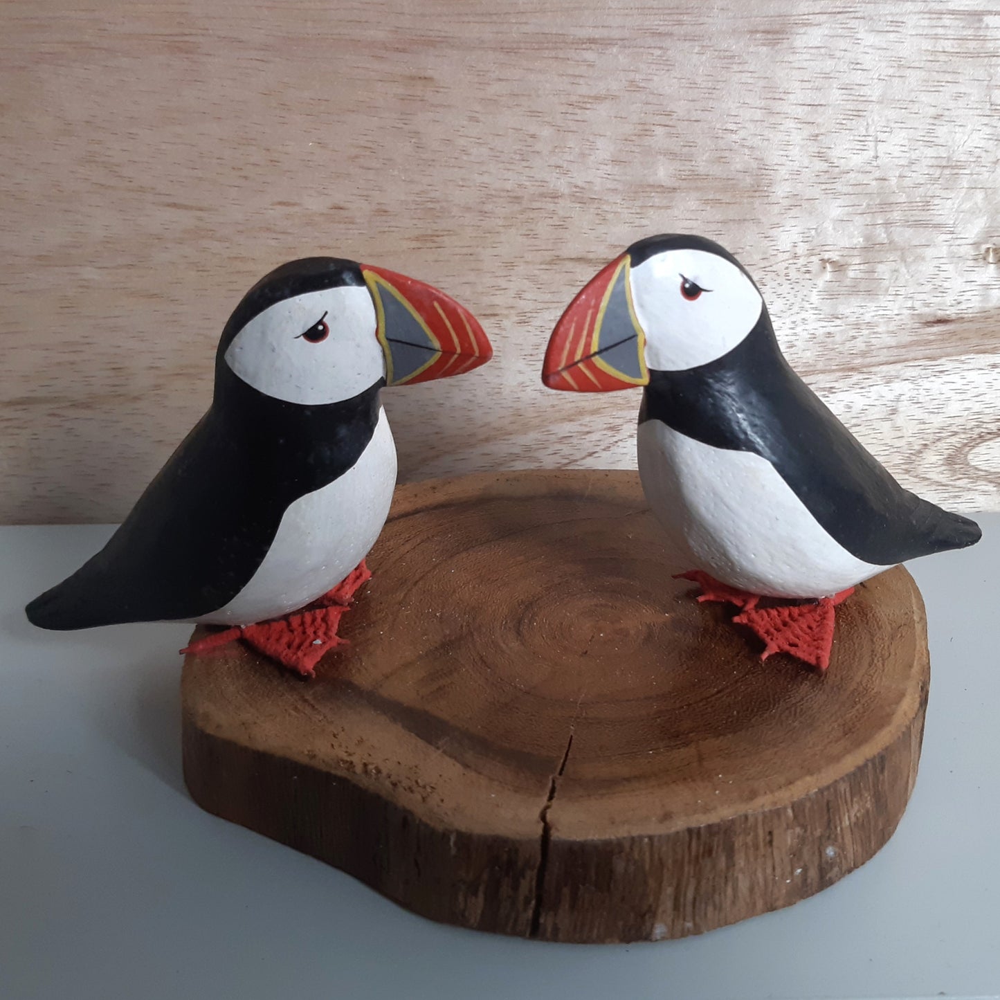 A set of 2 puffins mounted on a wooden base against a wooden background
