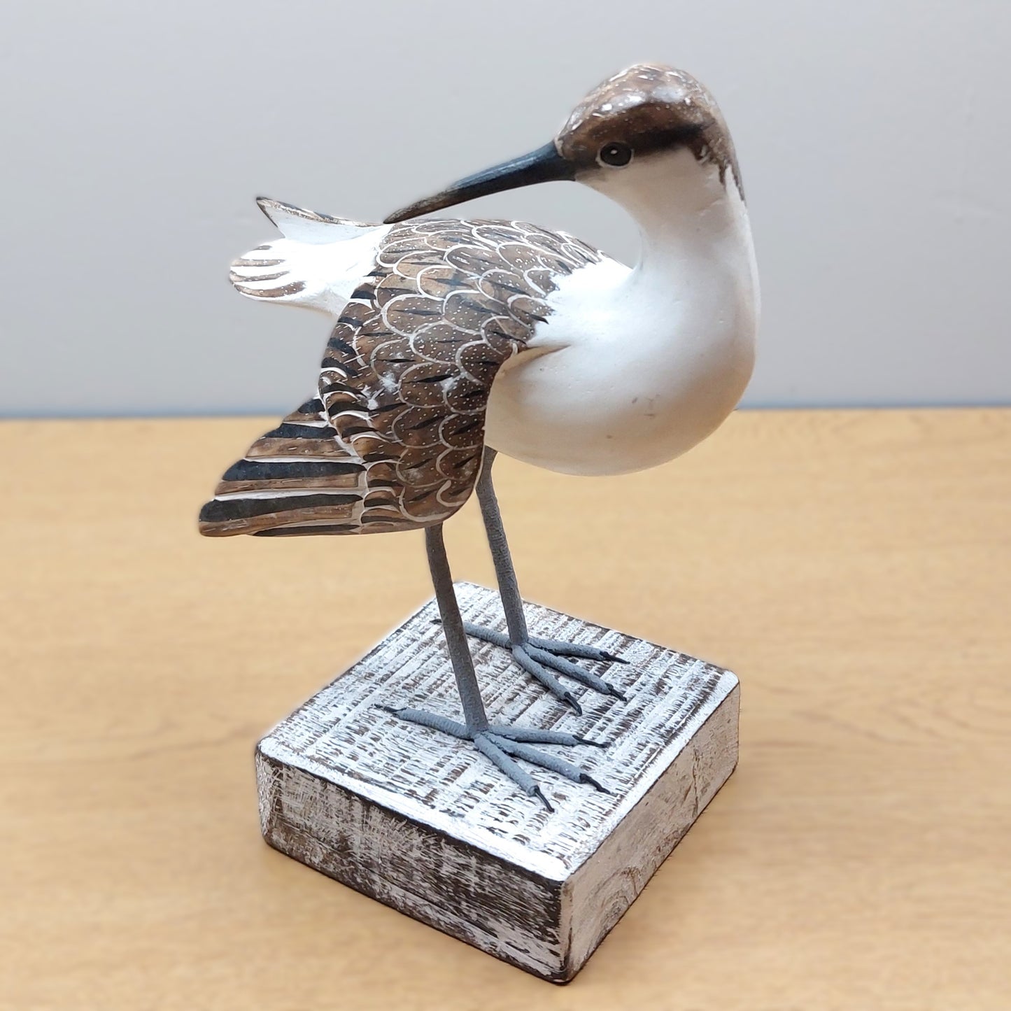 Decorative handmade and painted in Bali Godwit bird figurine on a wooden base with a plain background