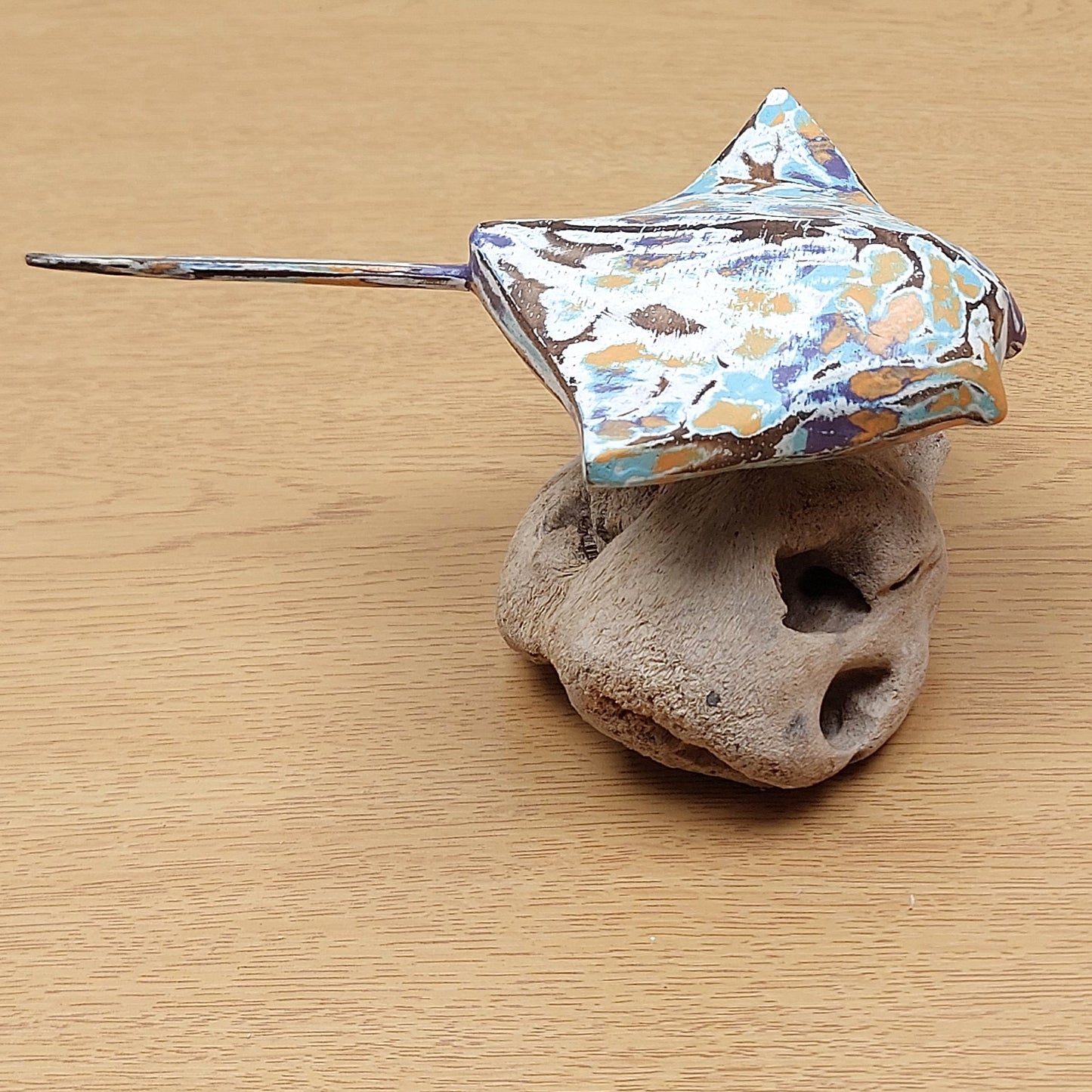 Decorative Manta Ray ornament on a piece of driftwood against a wooden background