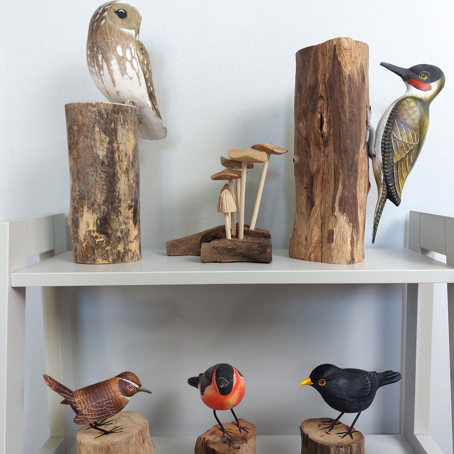 A selection of Cottagecore style wooden carved birds and mushrooms mounted on rustic style wood pieces against a pale background