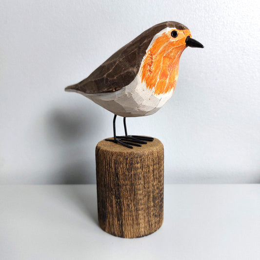 Wooden robin bird figurine on a cylindrical wooden base against a light background