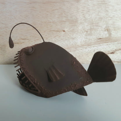 Brown rust style Allan the Angler Fish figurine on a light wooden surface