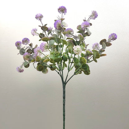 An artificial flower stem featuring purple thistle-like blooms and green eucalyptus leaves on a plain light background.