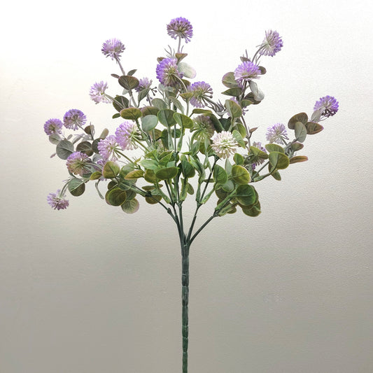 An artificial flower stem featuring purple thistle-like blooms and green eucalyptus leaves on a plain light background.