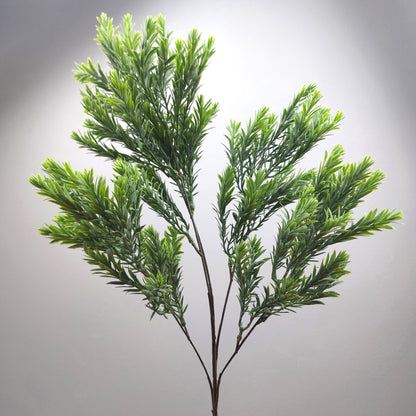 An artificial green leafy raven leaf spray or decorative plant stem with dense needle-like foliage on a plain light gray background.