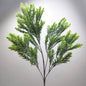 An artificial green leafy raven leaf spray or decorative plant stem with dense needle-like foliage on a plain light gray background.