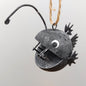 Decorative metal angler fish ornament on a plain background
