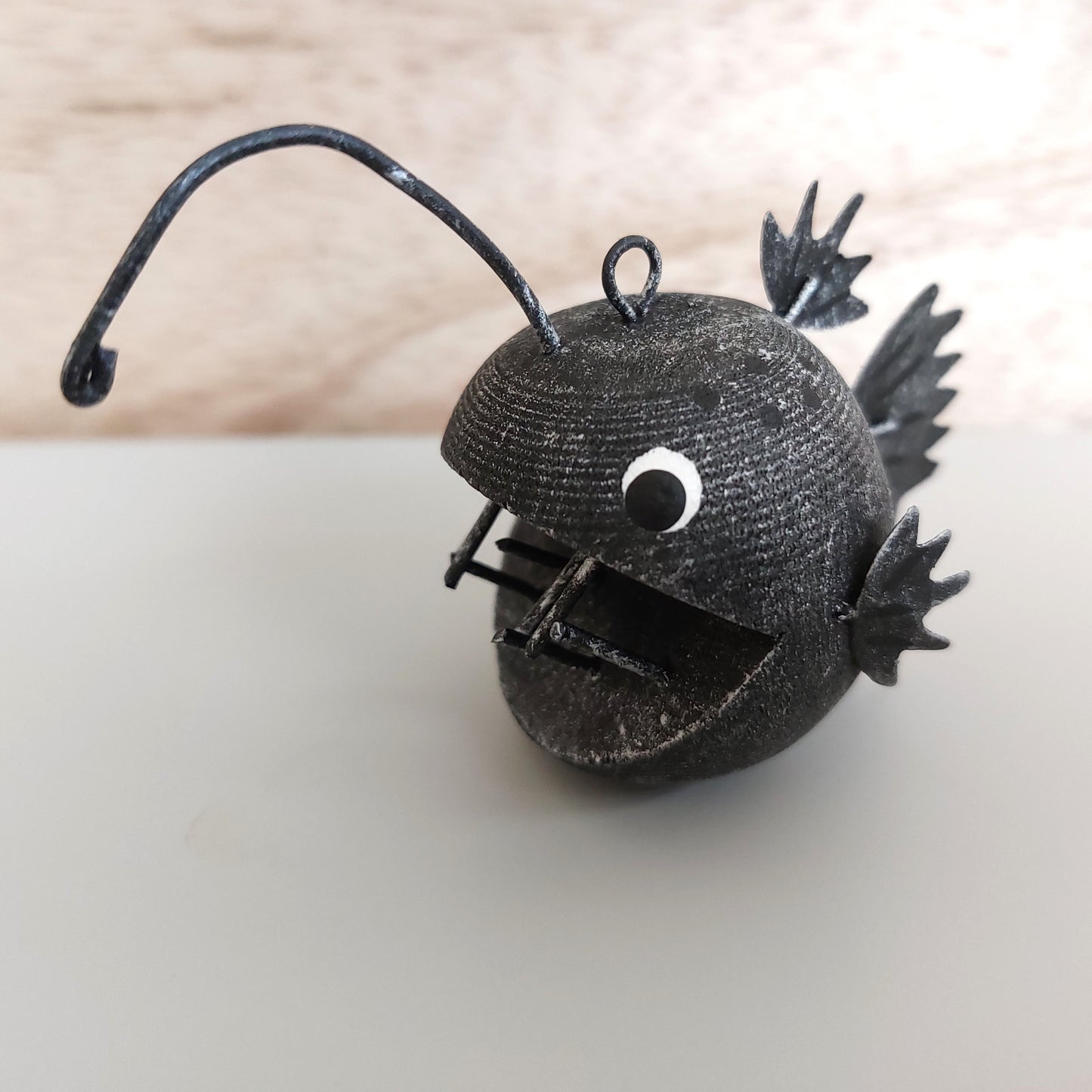 Black metal angler fish ornament on a light background