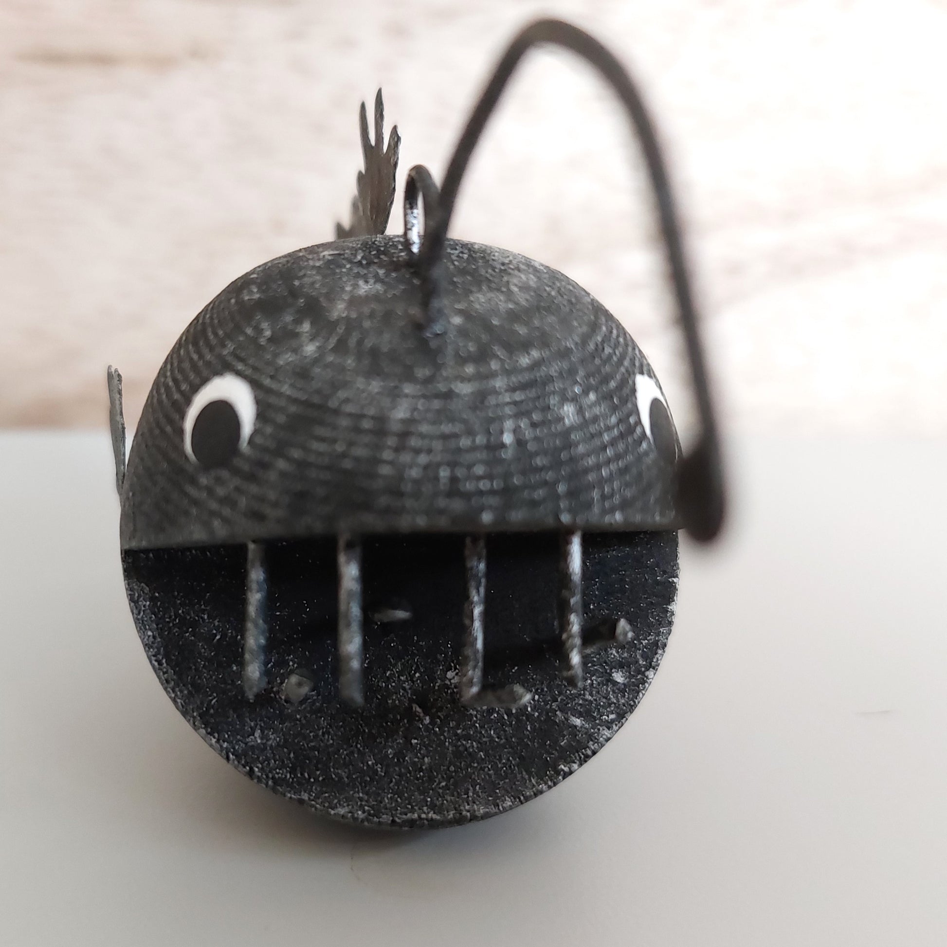 Black sculpture of an angler fish on a light wooden background