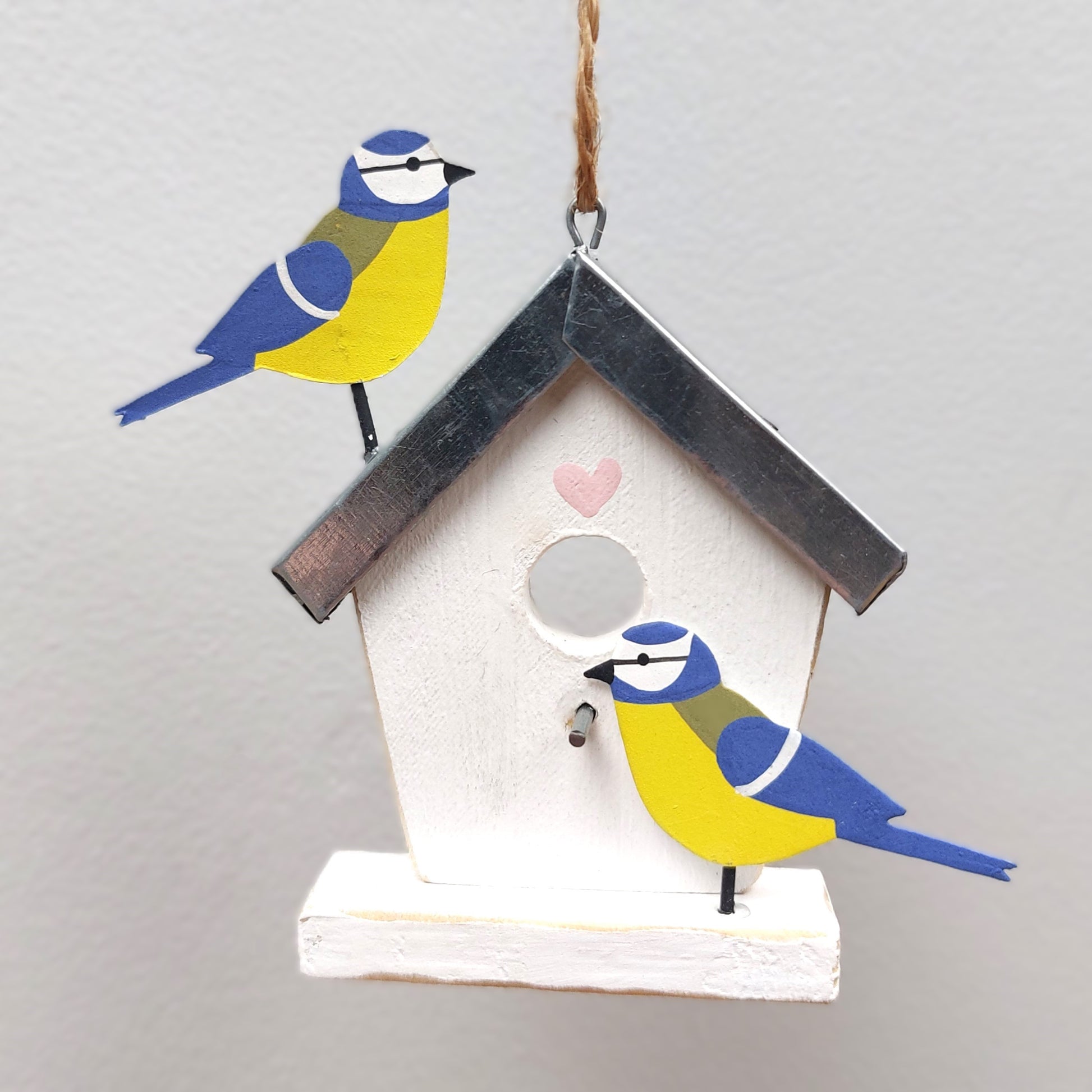 Decorative birdhouse wooden hanging decoration with painted birds on a plain background