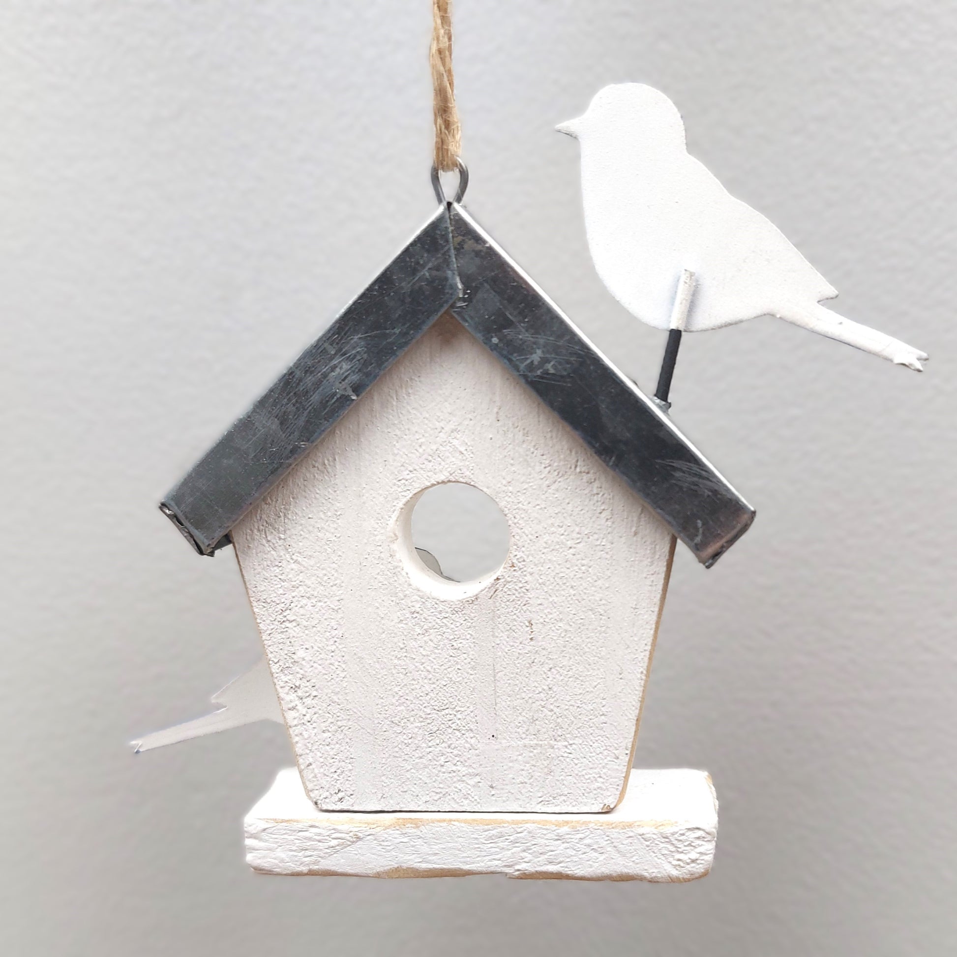 Reverse view of a Decorative birdhouse with a small white bird on a gray background