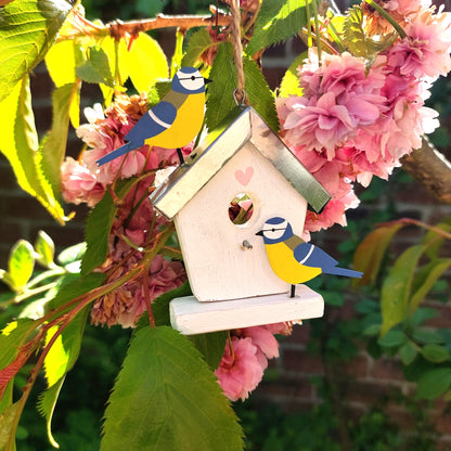 Decorative birdhouse with metal cute birds on a branch with pink flowers