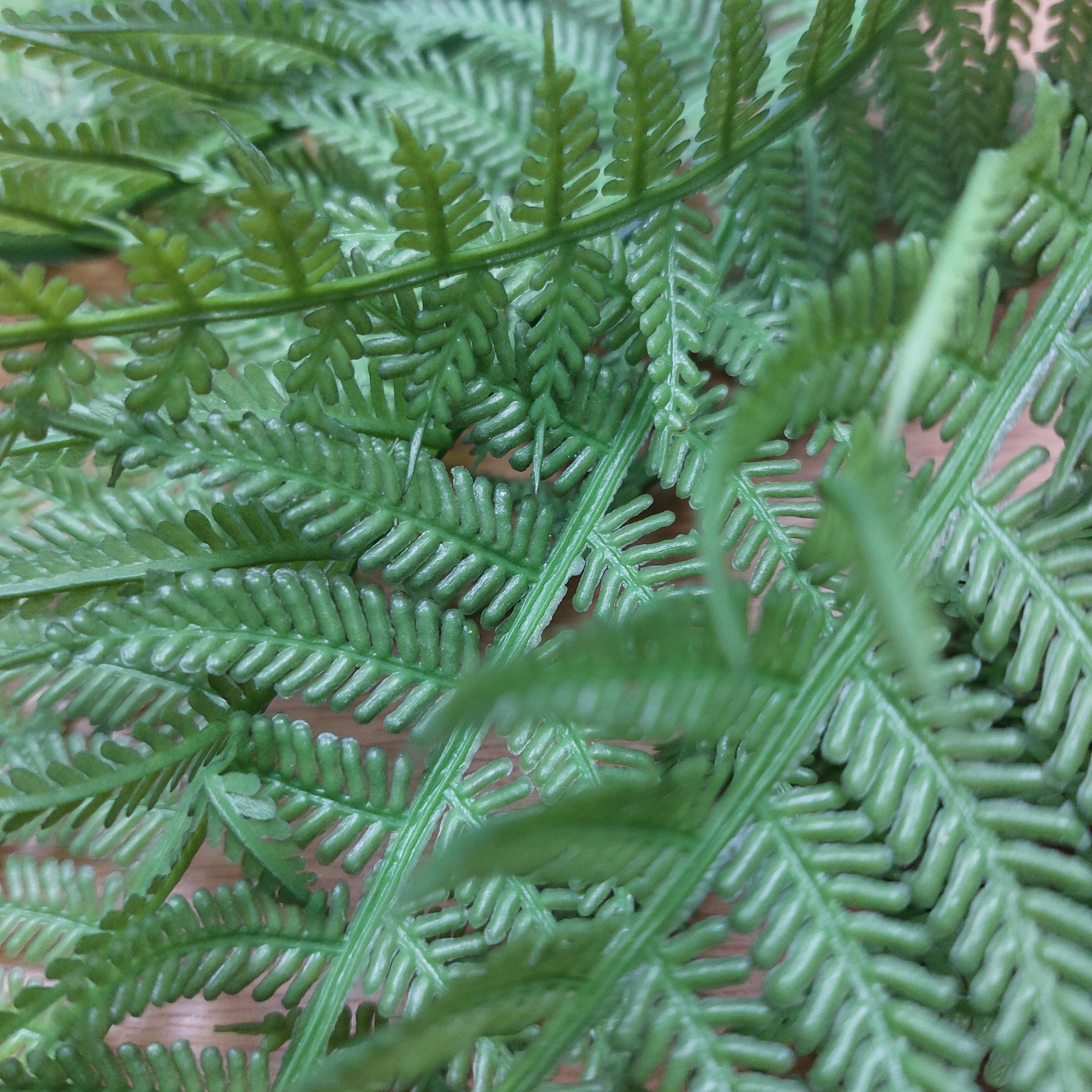Close-up of green artificial fern leaves with detailed, realistic fronds filling the frame.