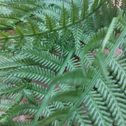 Close-up of green artificial fern leaves with detailed, realistic fronds filling the frame.