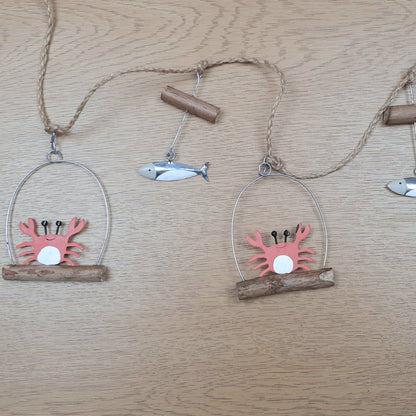 Close up of a decorative jute hanging garland with orange crabs and silver fish on a wooden surface
