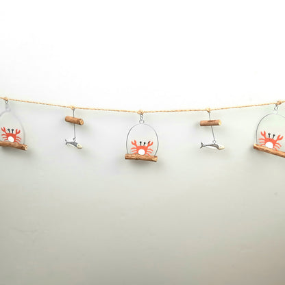 Decorative string with crab and fish ornaments on a plain background