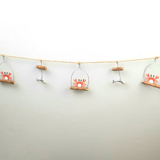 Decorative string with crab and fish ornaments on a plain background