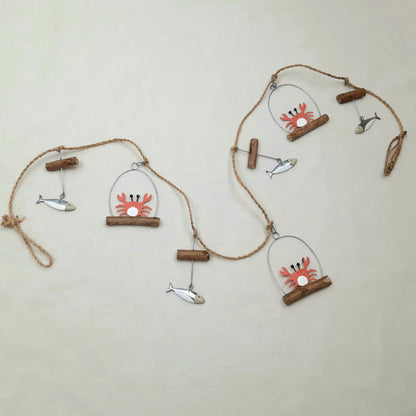 Decorative wall hanging with crab and fish designs on a beige background