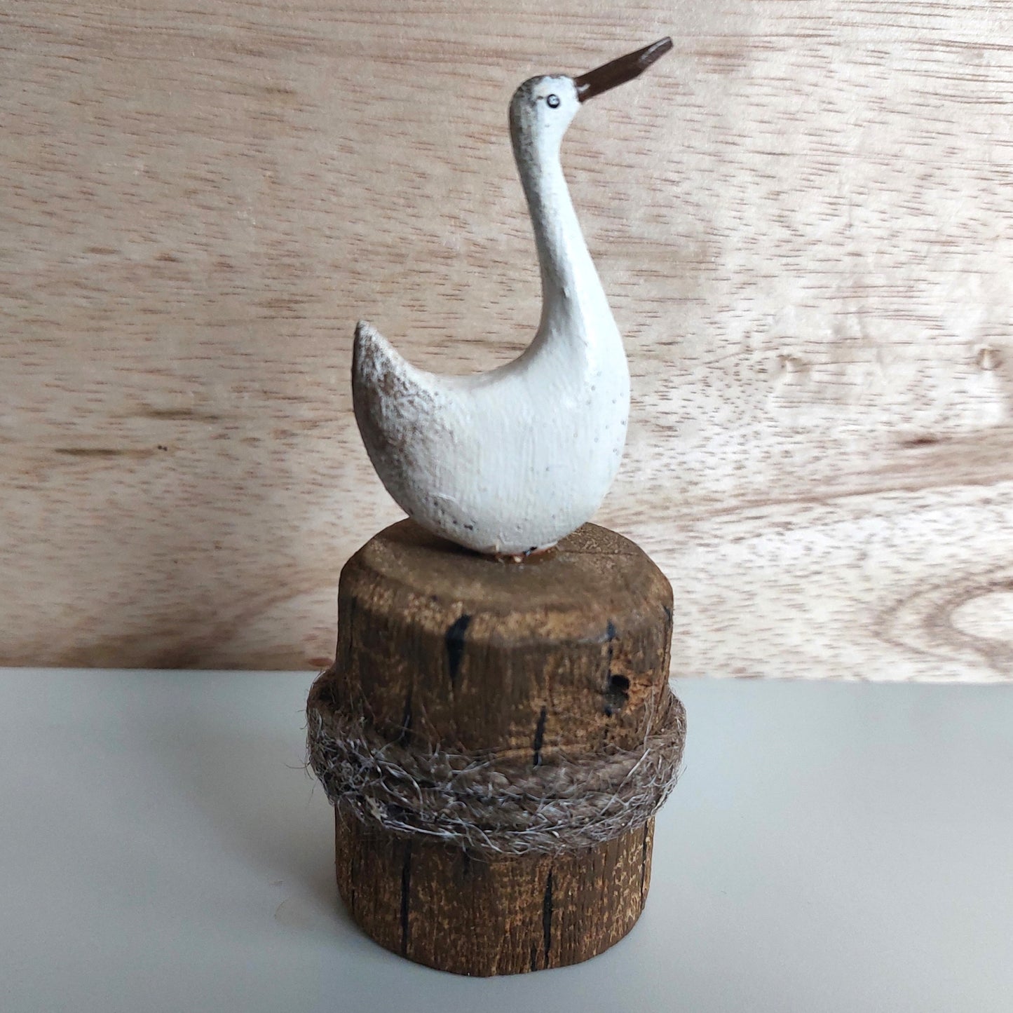 Decorative bird figurine on a wooden block with a natural wood background