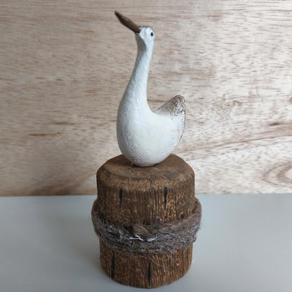 Decorative bird figurine on a wooden base against a wooden background