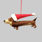 A brown felt sausage dog wearing a red Christmas hat, hanging from a red string against a white background