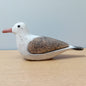 A wooden Seagull figurine, with a rustic detail effect against a pale background