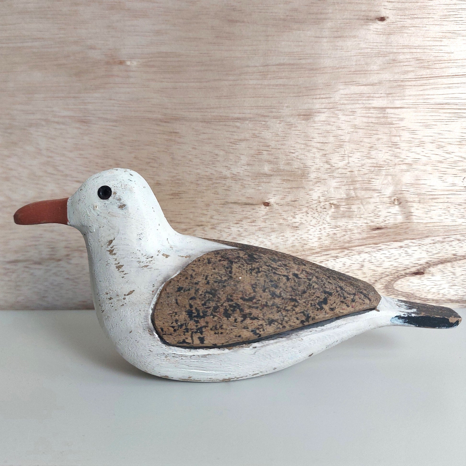 Wooden seagull figurine on a light wooden background