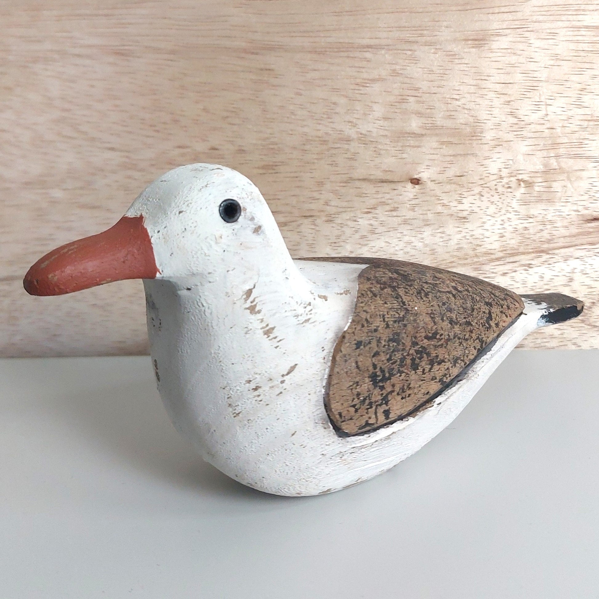 Wooden seagull figurine on a light wooden background