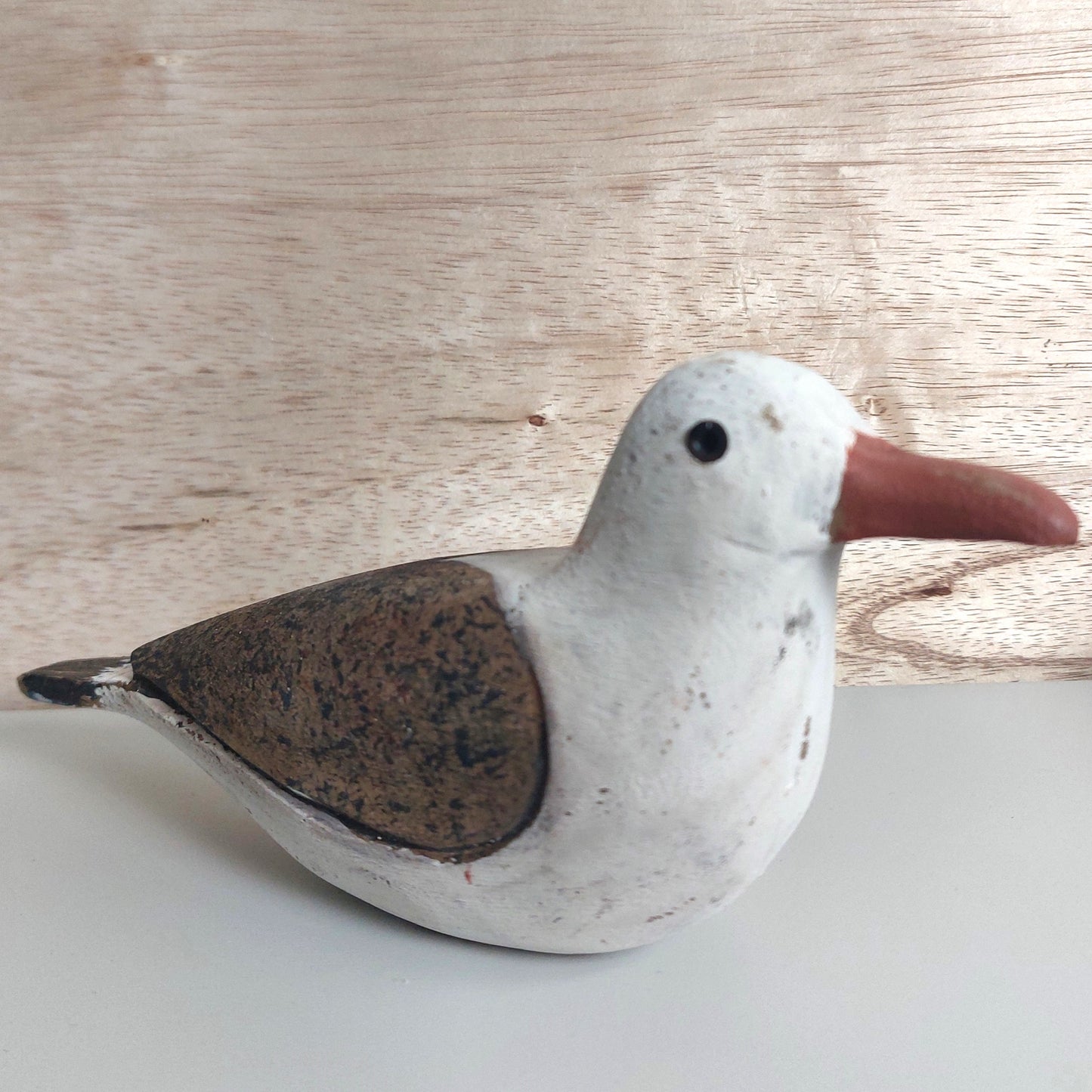 Decorative wooden hand painted seagull figurine on a light wooden background