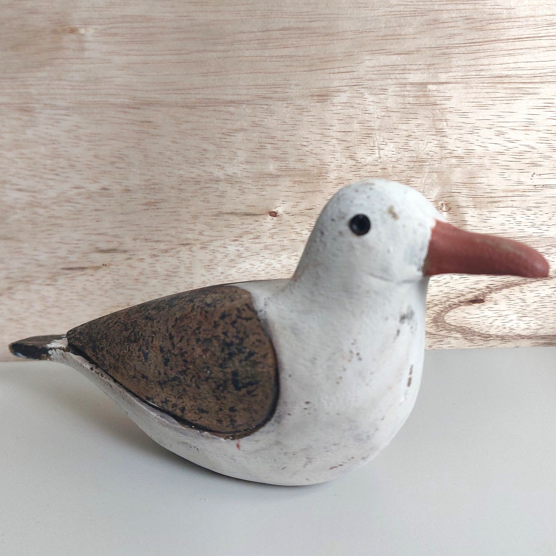 Decorative wooden hand painted seagull figurine on a light wooden background