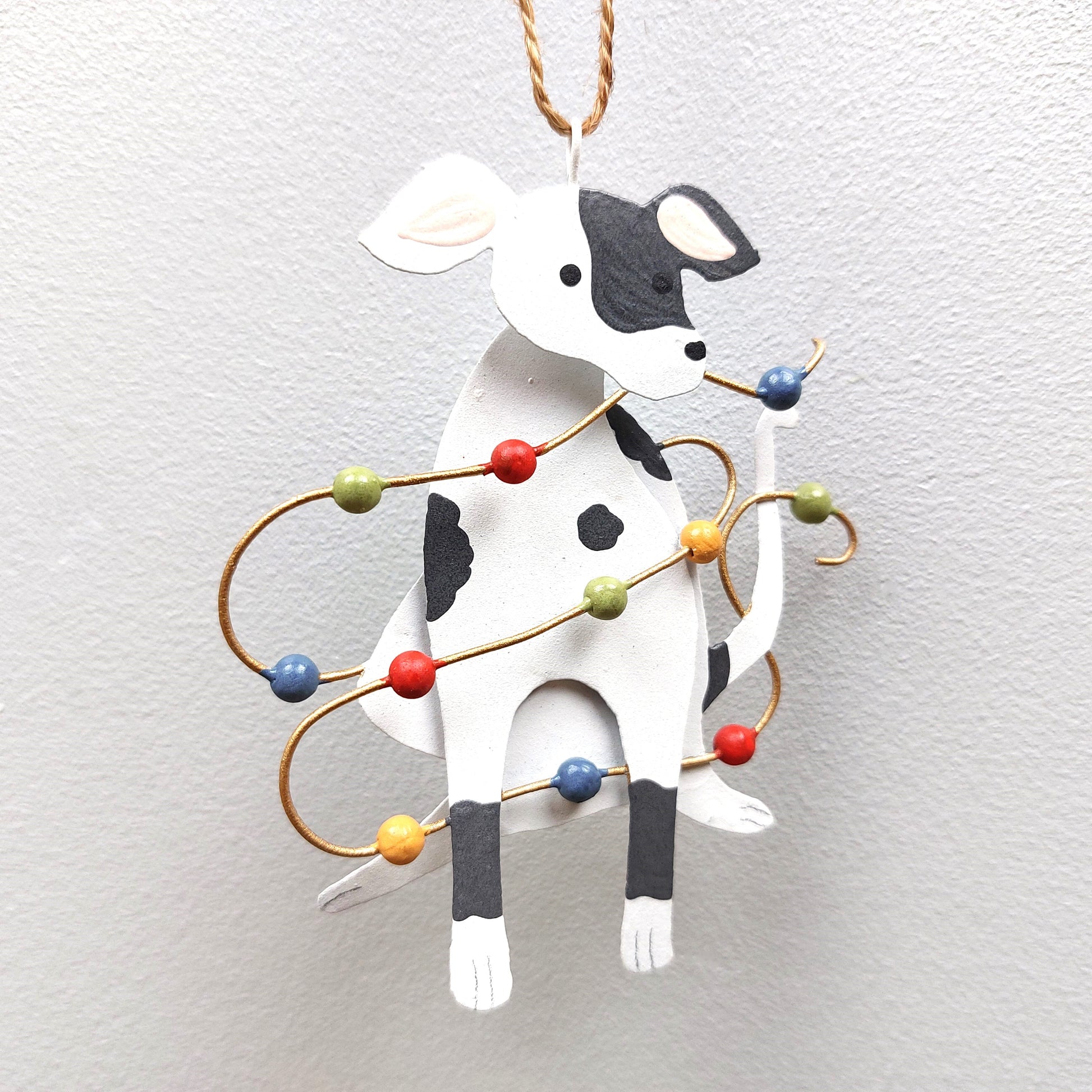 A tin spotty dog decoration with Christmas lights against a white background