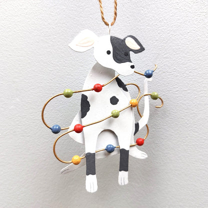 A tin spotty dog decoration with Christmas lights against a white background